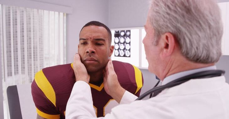 doctor examining injured rugby player's ear and head