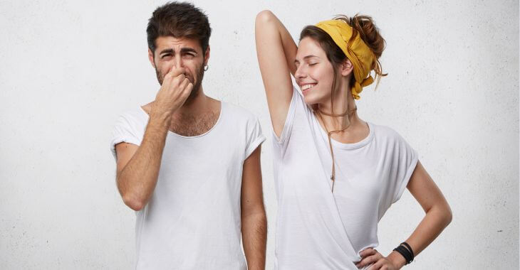 A young man blocking his nose because of the body odor coming from a young woman standing next to him