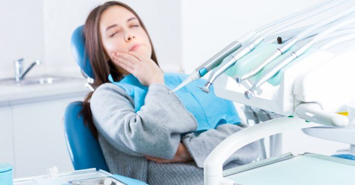 Young woman with severe toothache in a dental chair before root canal procedure
