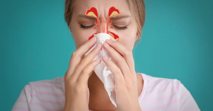 Woman with sinus infection blowing her nose.