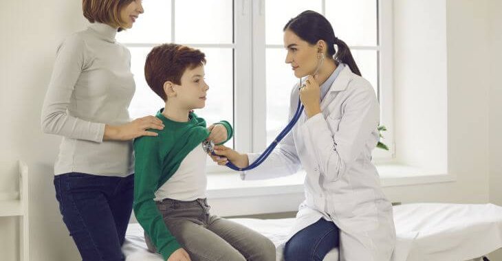 A boy assisted by his mother during doctor's appointment for precordial catch syndrome diagnosis.