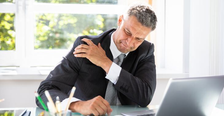 A businessman at work suffering from shoulder arthrosis pain.