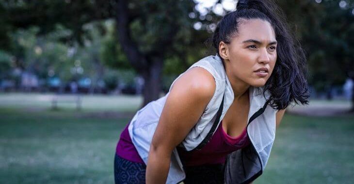 Sporty woman breathing through her mouth when resting after exercising in a park.