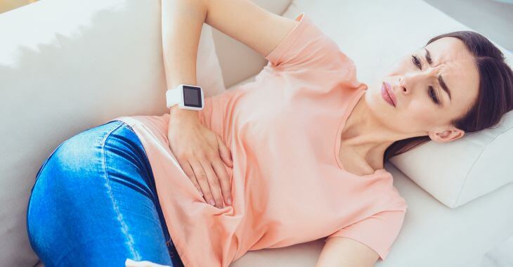 Woman with hernia touching her abdomen.