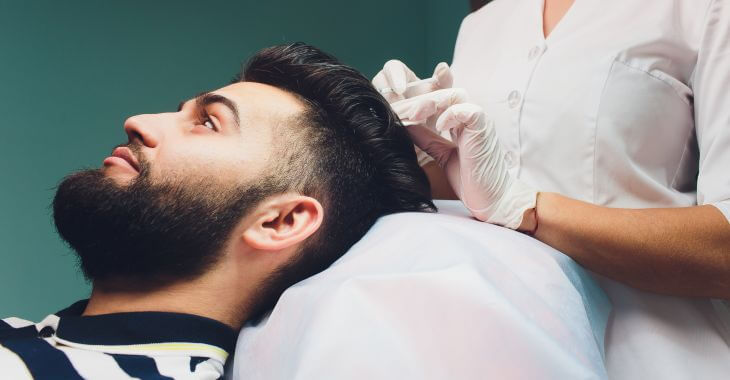 A man with dark hair and beard receiving PRP treatment for hair loss.
