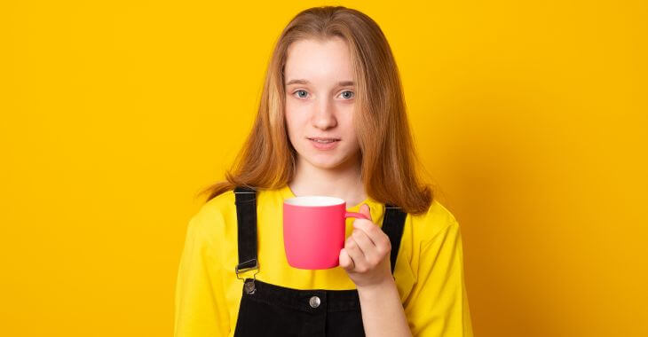 An adolescent girl with a mug of coffee.