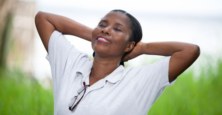 A happy Afro-American woman spending time outdoors breathing deeply fresh air.