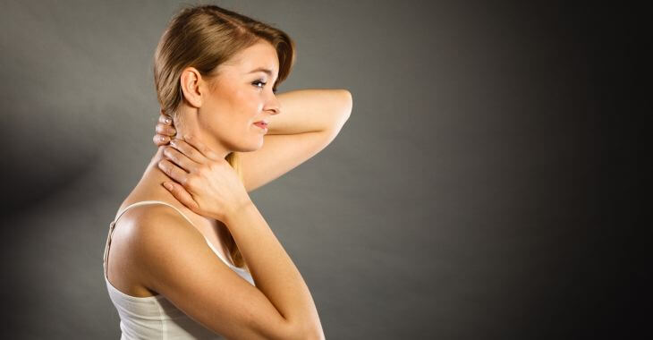 A woman touching a lump on the back of her neck.