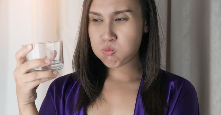 Woman drinking water after waking up with dry mouth.