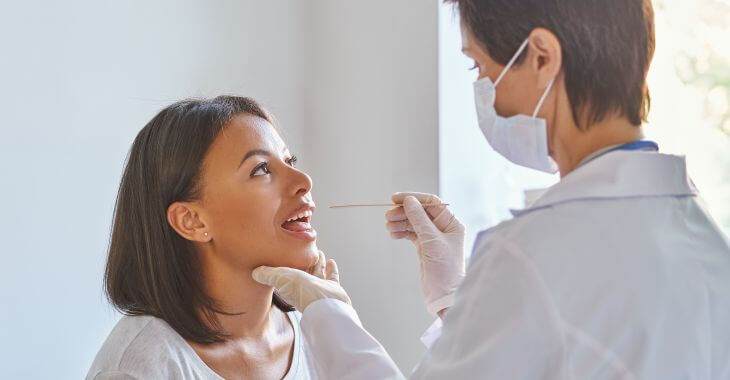 A doctor examining woman's throat.