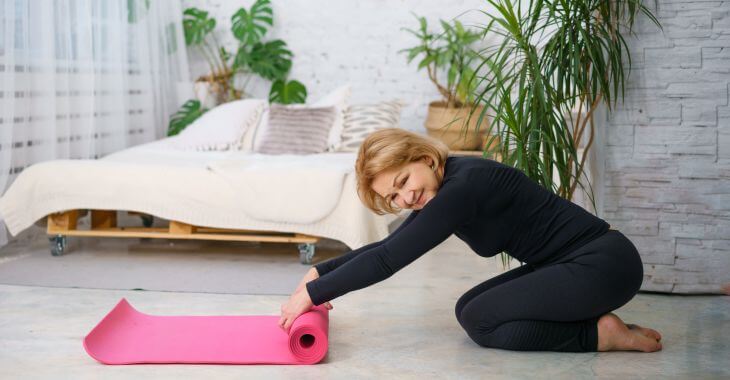 Mature woman doing stretching exercises before going to sleep.