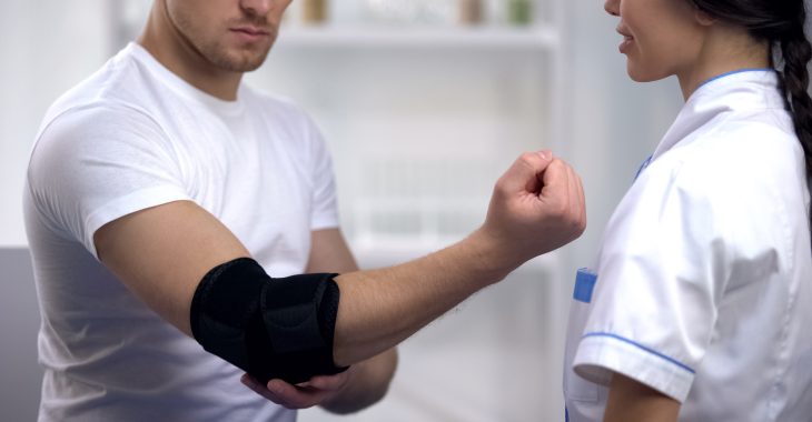 A doctor advising an athletic man on elbow brace.