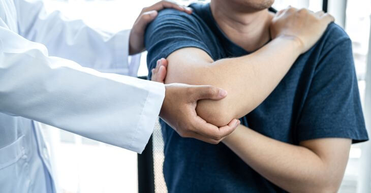 A doctor consulting a man with shoulder pain.