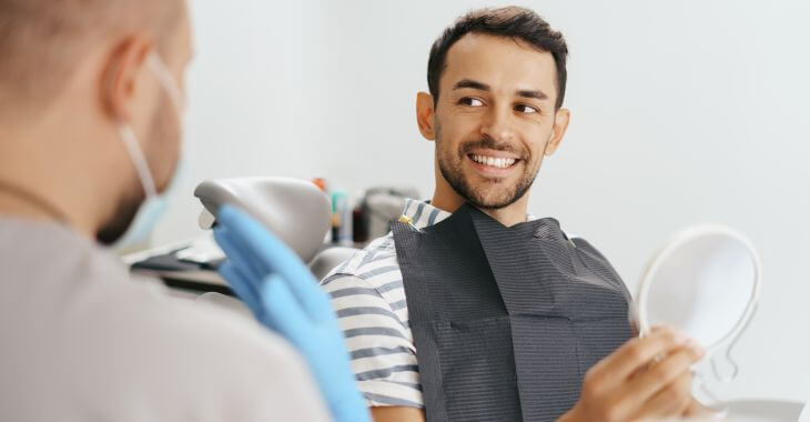 A dentist and a smiling man in a dental chair during a post-treatment appointment.