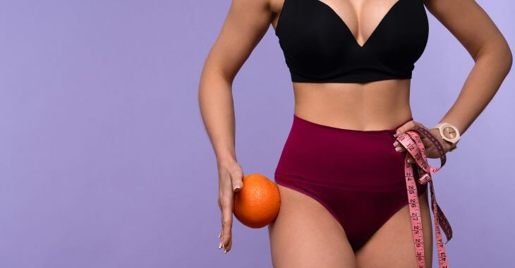 Silhouette of a slim woman wearing underwear holding a measurement tape and an orange.