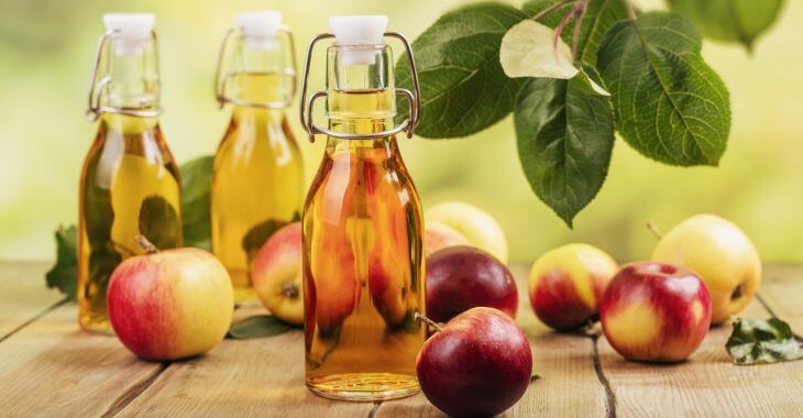 Bottles of vinegar among apples.