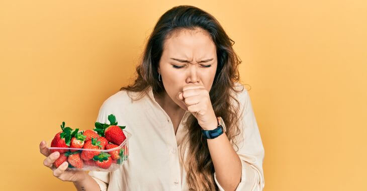 Coughing woman holding a package of strawberries. 