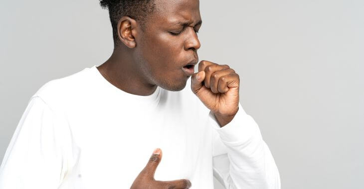 Coughing Afro-American man feeling pain in abdomen.