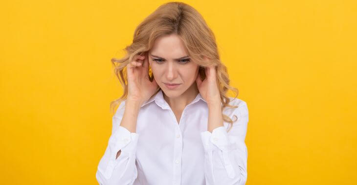 Woman pressing her ears due to hearing crackling in ears.