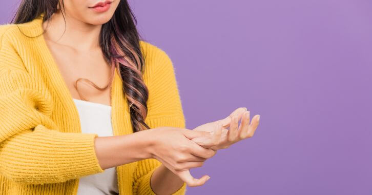 Young woman massaging her swollen hand.