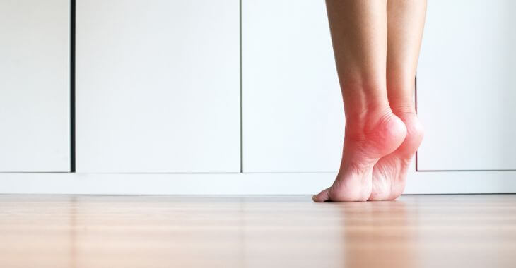 Barefoot woman climbing on het toetips while doing stretching exercises. 