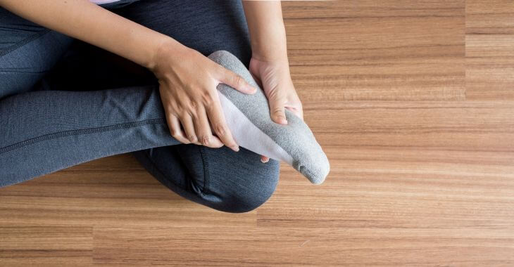 A person wearing compressing socksmassaging their sole.