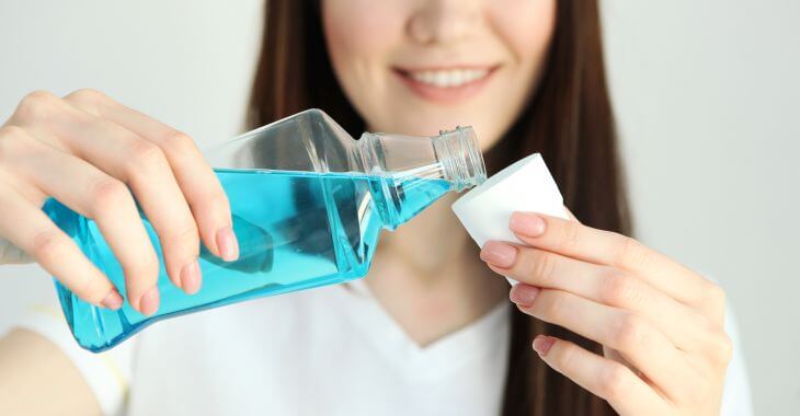 Woman pouring mouthwash into a cup,