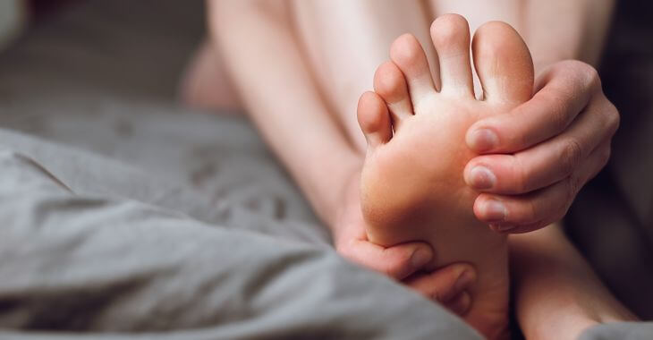 A person massaging their painful foot and pinky toe.
