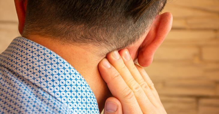 Man touching painful area behind his ear.