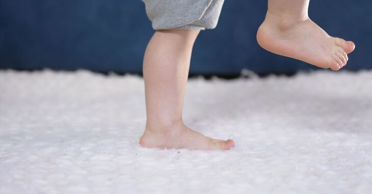 Toddler walking on a carpet.