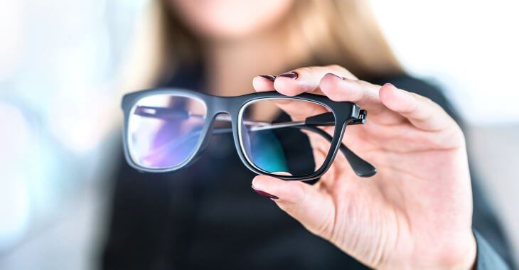 Woman presenting a pair of bifocal glasses.