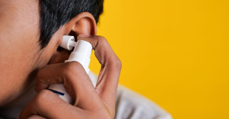 A man using ear wax removal spray.