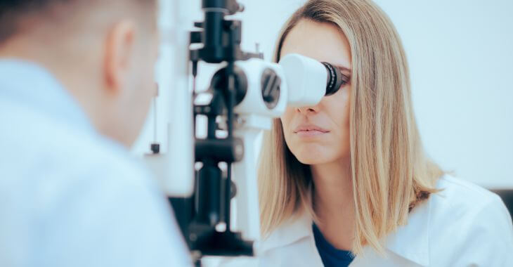 A doctor using medical equipment to diagnose patient's eyes.