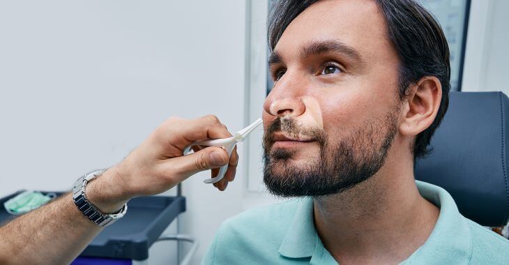 ENT doctor examining man's nose and nostrils.
