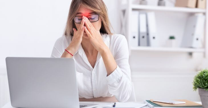 A businesswoman suffering from headache caused by dry sinuses.