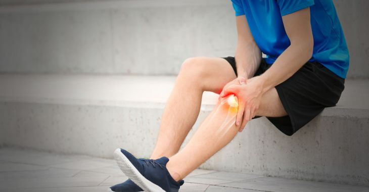 A man suffering from knee pain sitting on stairs.