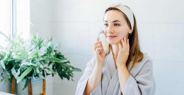 A woman using ice-roller for face as a part of skincare routine.