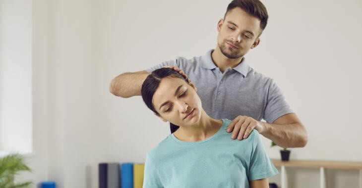 Osteopathic doctor showing a woman with tighten neck how to perform levator scapulae stretch.