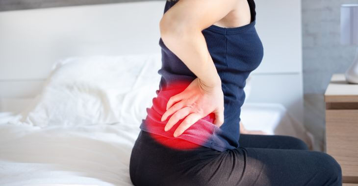 A woman with side hip pain after sitting on the edge of the bed.