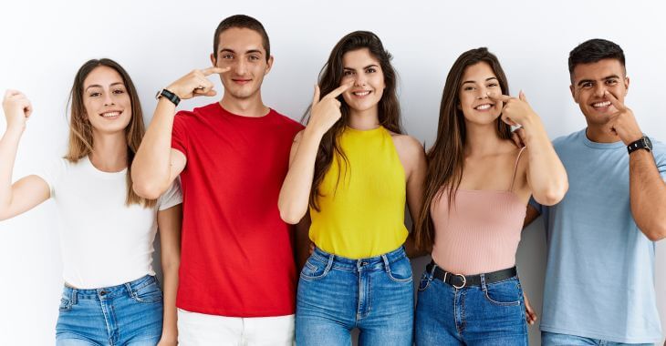 Multicultural group of people pointing at their noses.