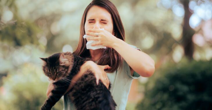 Sneezing woman carrying a cat.