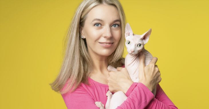 A woman holding a Sphynx cat in her arms.