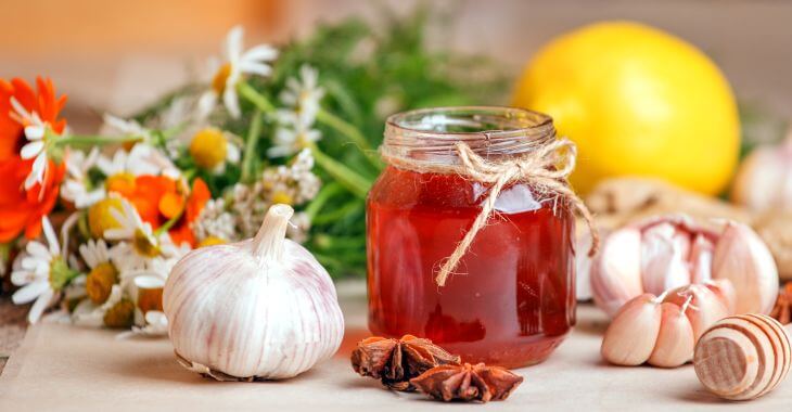 Garlic, a jar of honey and spices on a kitchen table.