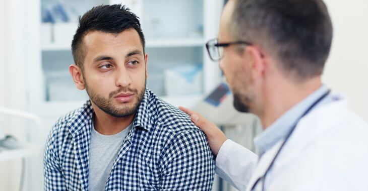 A doctor explaining treatment options and cheering up a concerned young man.