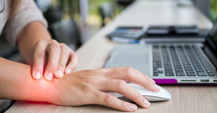 Woman with wrist pain from typing working on a laptop 