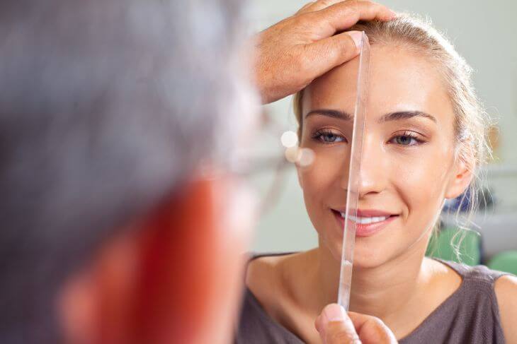 A plastic surgeon measuring woman's nose and face proportions