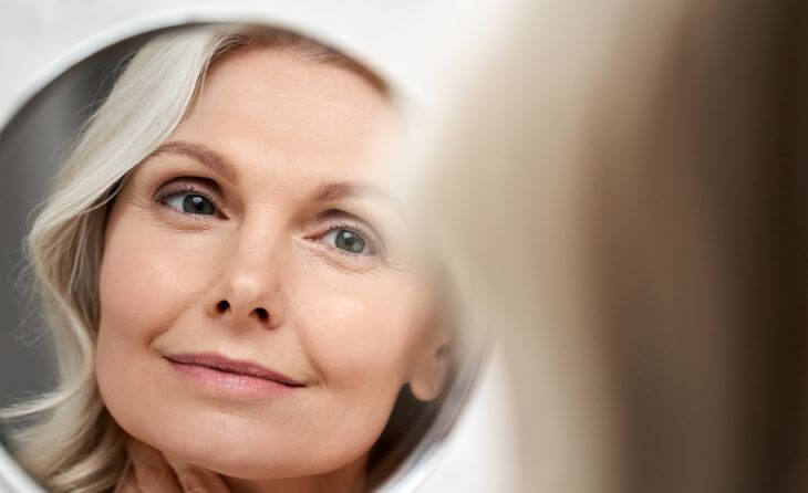 middle-aged woman looking at her face in a mirror