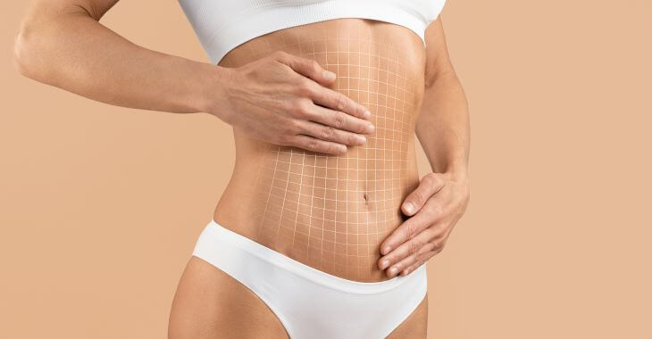 Slim woman with flat abdomen massaging her tummy