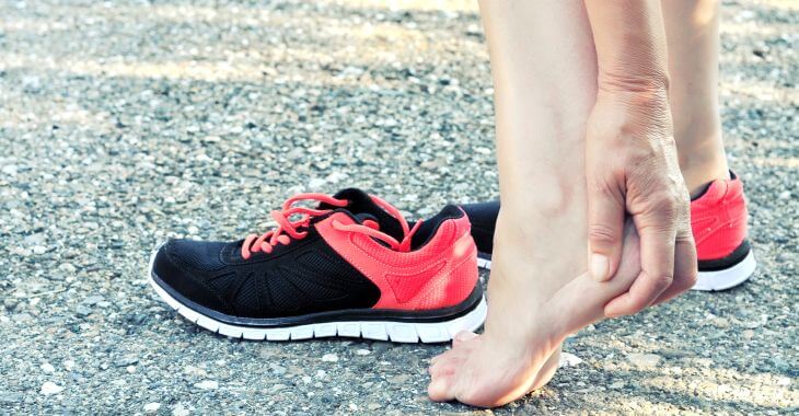 woman who's taken off her running shoe massaging her painful heel cause by running