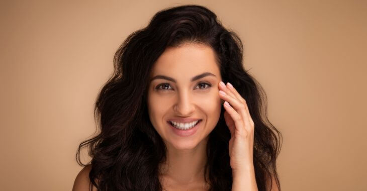 Happy beautiful woman touching the skin under eye